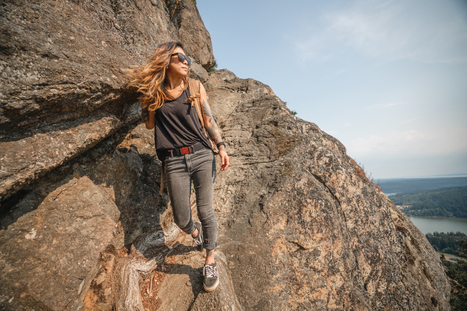 Molly Hawkins hiking down a rock face above the water in the Pacific Northwest